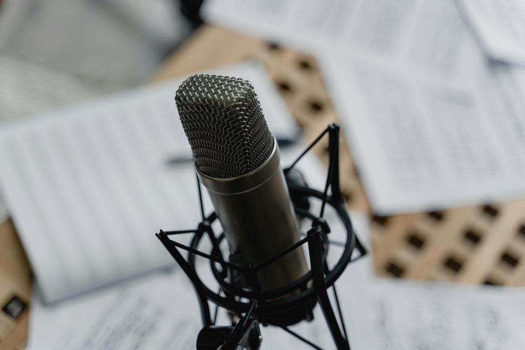 Professional Voice Artist Bilingual in English and Welsh 1 A microphone surrounded by scripts that show why it is important to choose a human voice for your project